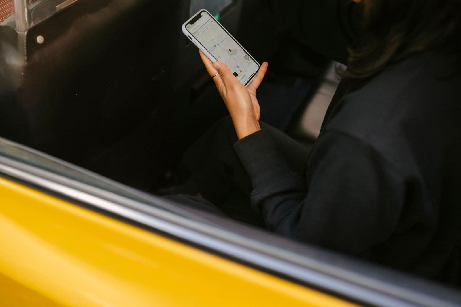 Passenger using a ride-hailing navigation app on a smartphone in a car